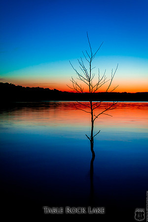 Table Rock Lake red sunset with blue sky and tree silhouette with reflection